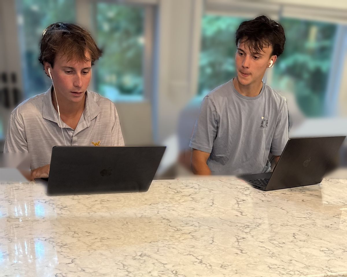 Grant and Owen Stropkai working on laptops at a kitchen counter